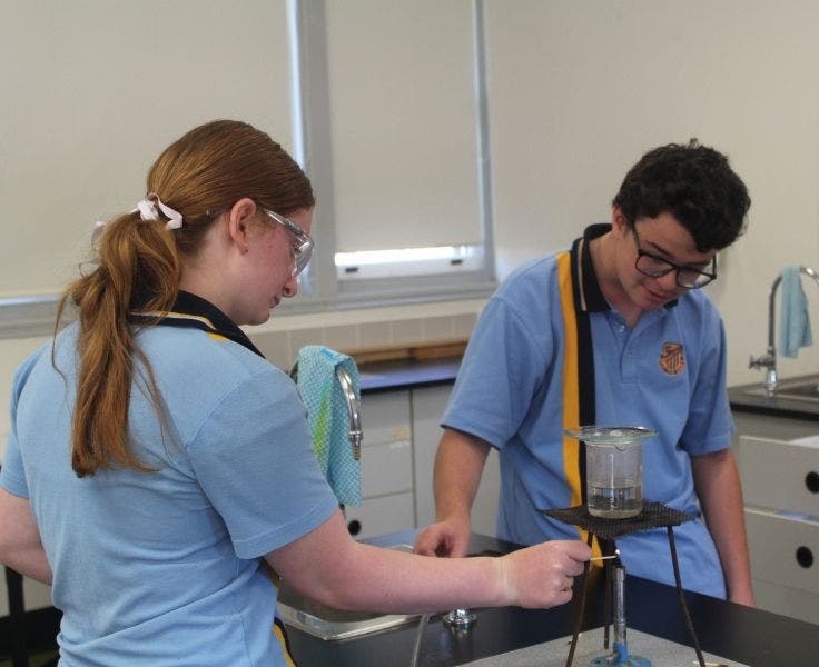 Two students conducting an experiment with a Bunsen burner in the science lab.