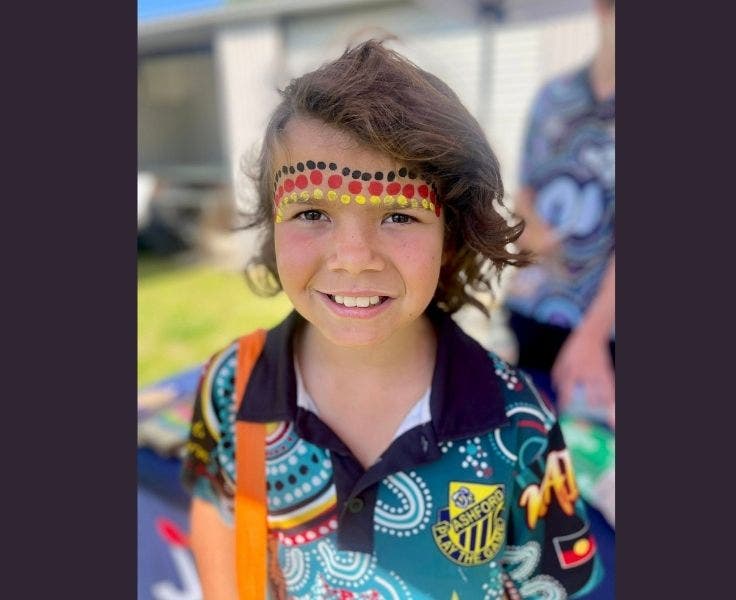 Student wearing a Naidoc shirt and black, red and yellow dots painted on her face in a traditional design