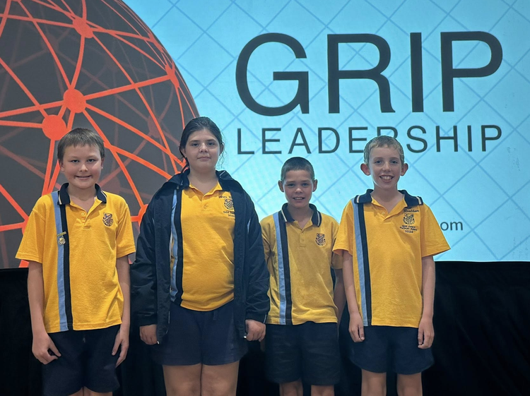 Four students standing in a line in front of the grip leadership banner